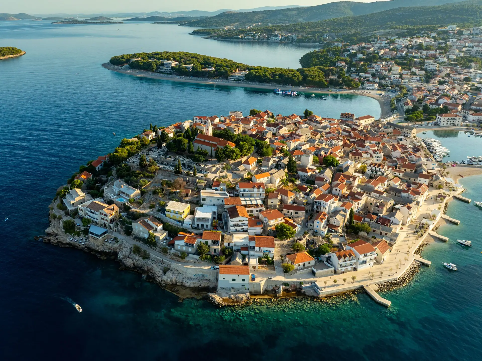 Aerial view of a red-roofed coastal town on a peninsula surrounded by turquoise Adriatic waters